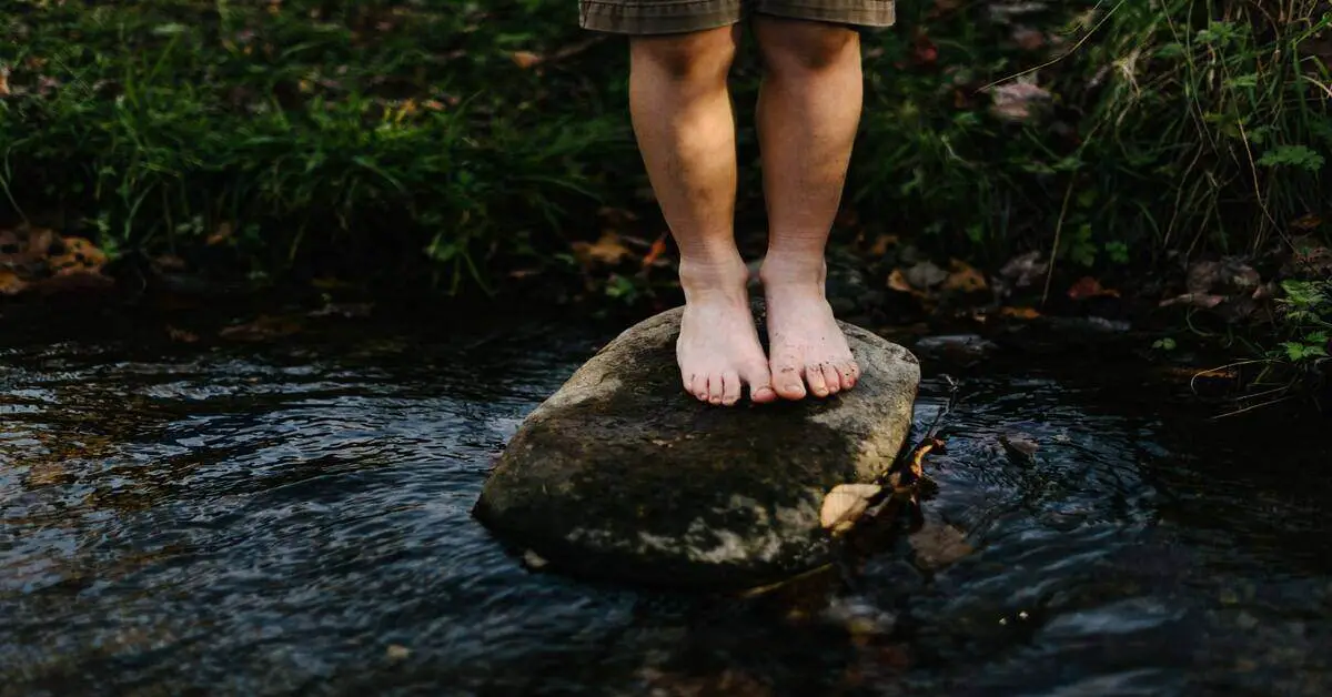 hiker cleaning feet at a stream