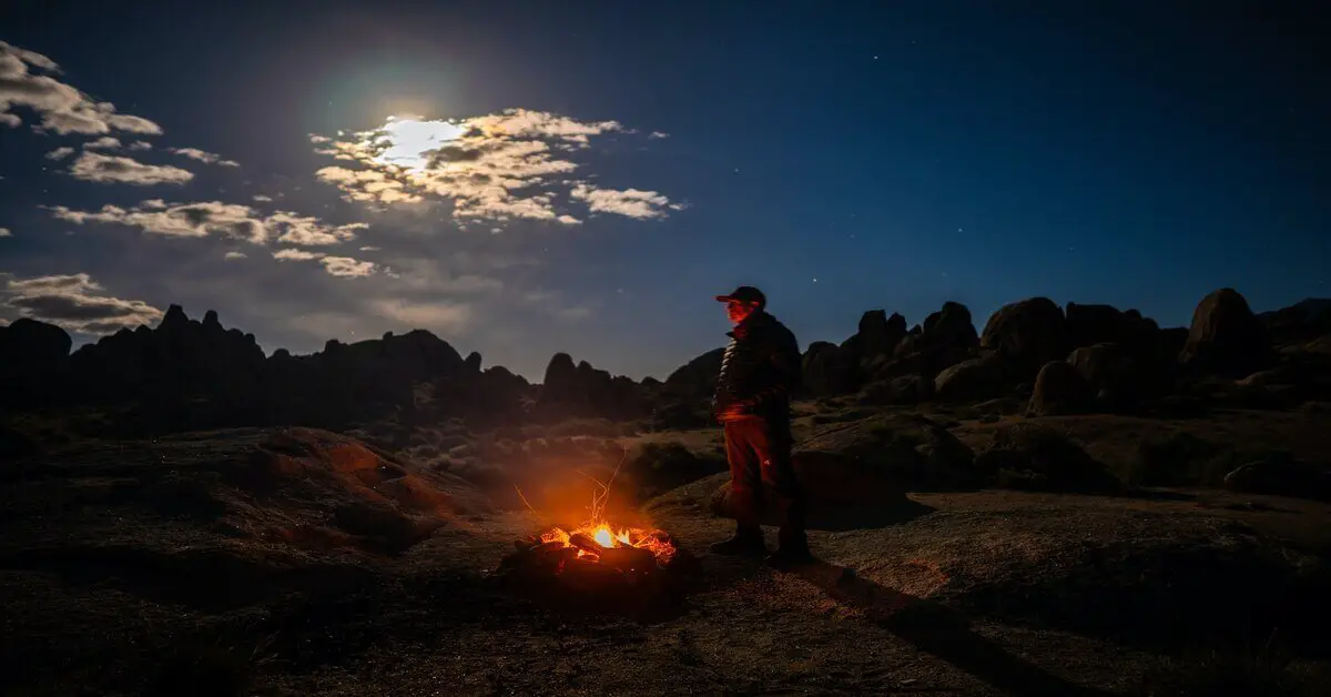 man standing next to campfire