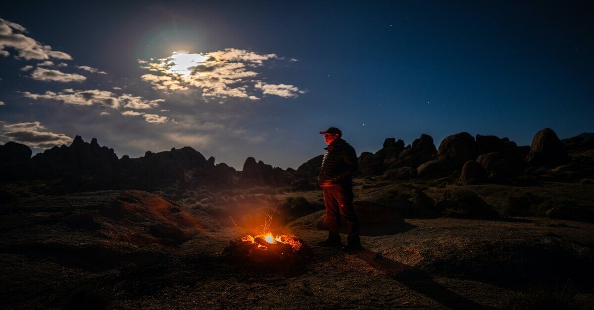 man standing next to campfire