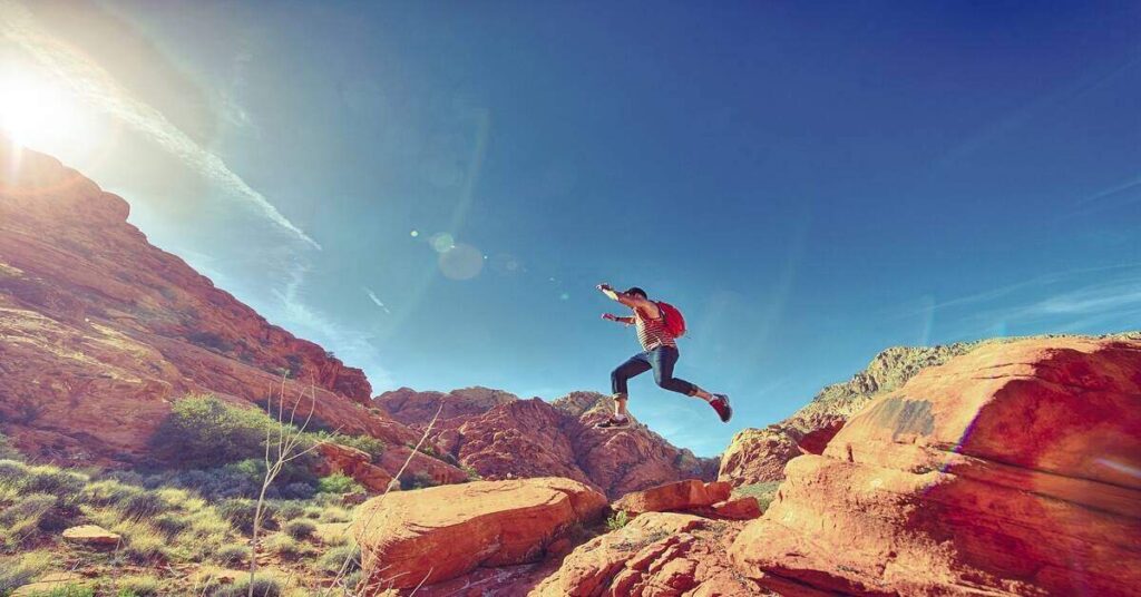 hiker jumping over rocks