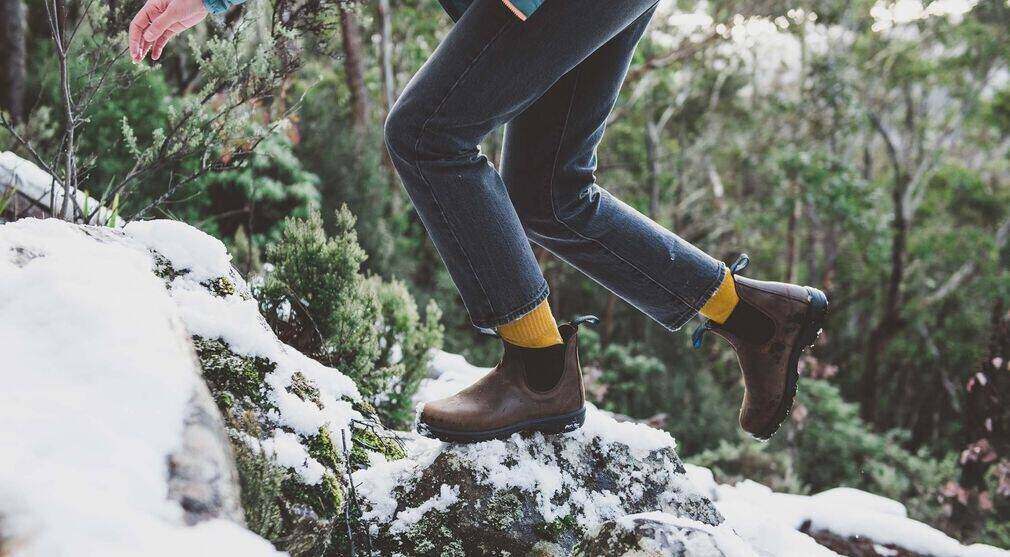 Woman climbing over rock in blundstones