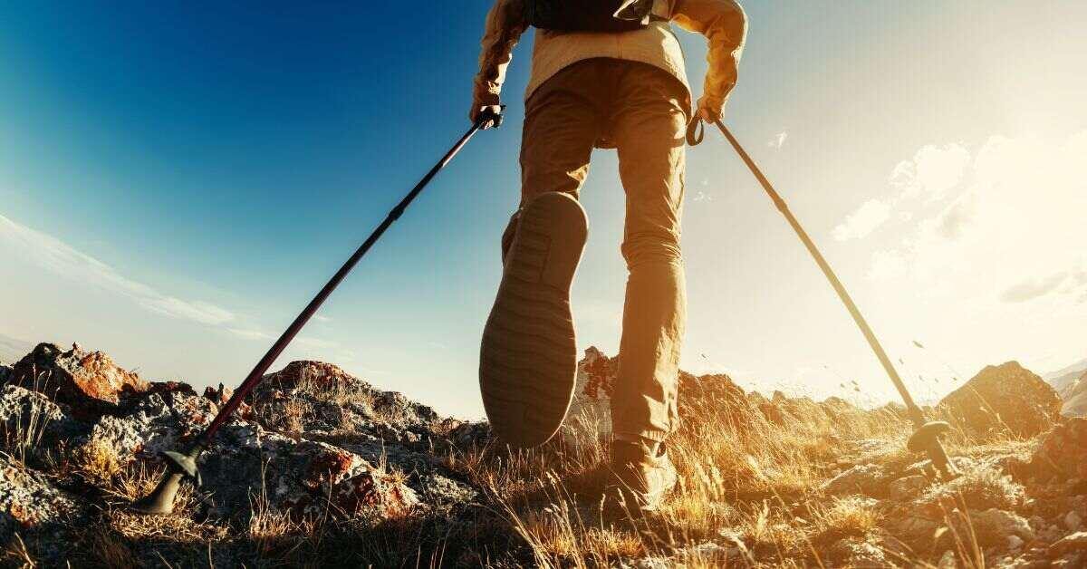 Up-close image of hiker climbing a hill with trekking poles
