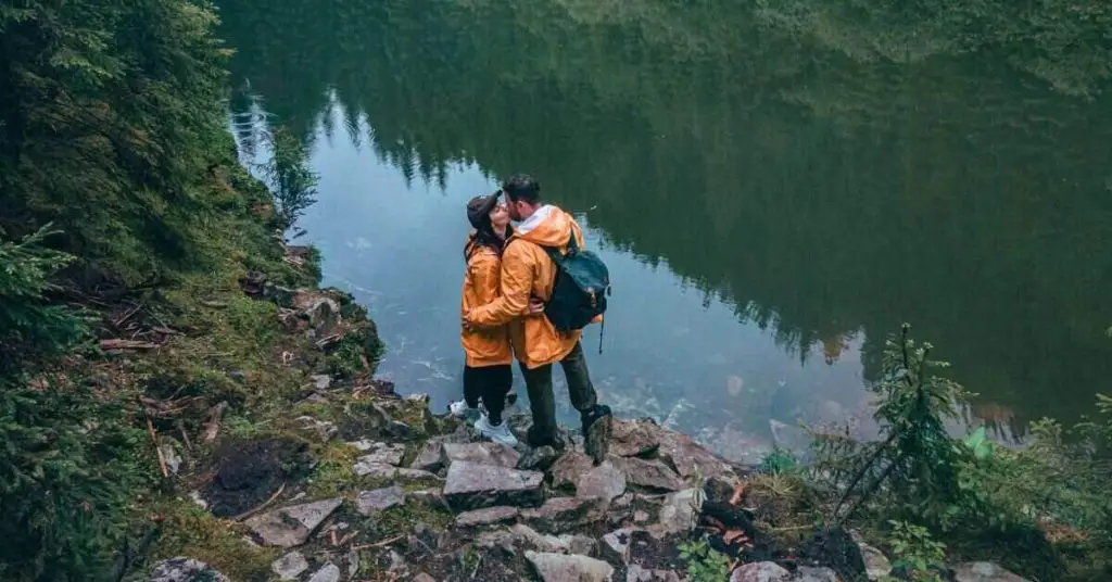 two hikers holding each other near lake