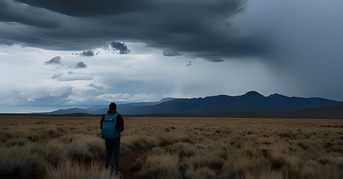 Image of a hiker on a trail looking at dark skies